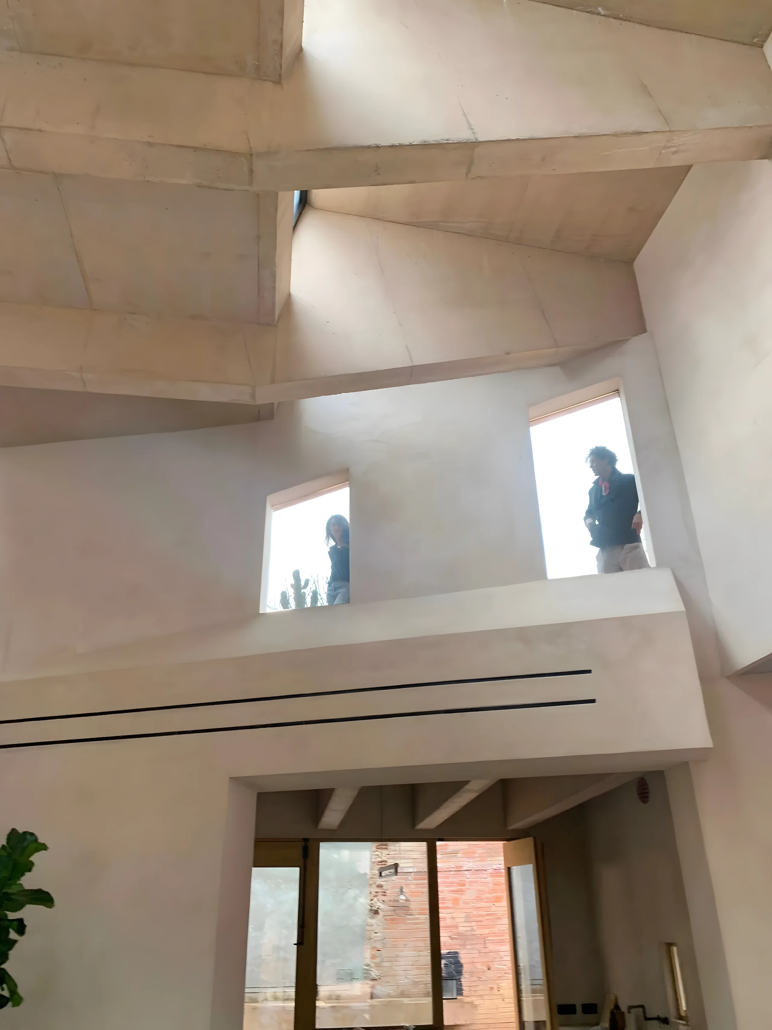 Dos figuras asomadas a los huecos altos de la casa